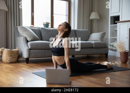 Concentrato giovane ragazza yoga pratica yoga a casa Foto Stock