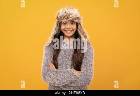 bambino positivo in maglione e cappello con archetto su sfondo giallo, moda stagione Foto Stock