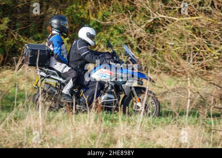 Motociclista e passeggero del pilone su una moto BMW R1200 GS che viaggia attraverso la campagna invernale Foto Stock