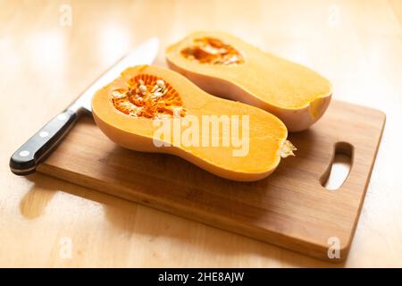 Zucca di butternut (Cucurbita moschata)-mcut a metà su un fuoco selettivo di bordo di trinciatura Foto Stock