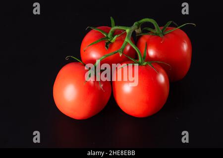 Pomodori freschi biologici su sfondo nero. Pomodoro rosso maturo. Foto Stock