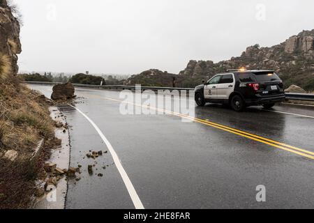 Los Angeles, California, USA - 30 dicembre 2021: Auto della polizia di Los Angeles che osserva la piccola pioggia imbevuta di frana sulla Santa Susana Pass Road. Foto Stock