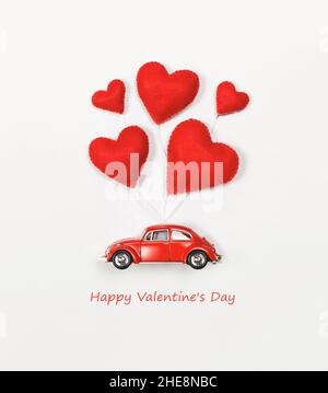 San Valentino e Festa della mamma sfondo. Cuori rossi e auto retrò su sfondo rosa. Foto Stock