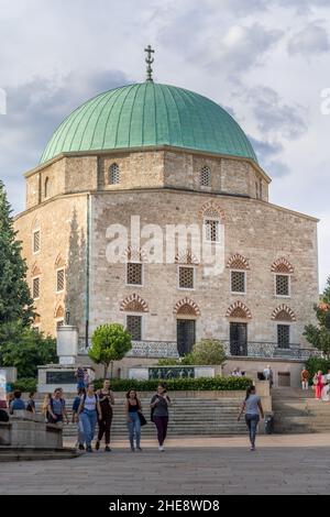 Gli studenti passano accanto alla moschea di Pasha Qasim che ora serve come chiesa catolica nella città universitaria alla moda di Pecs nell'Ungheria meridionale Foto Stock