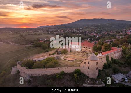 Scatto aereo al tramonto della chiesa fortificata di Pecsvarad e del castello con torre, porta sulla cima di una collina nella contea di Baranya Ungheria Foto Stock