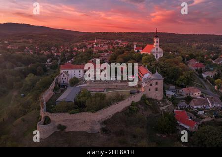 Scatto aereo al tramonto della chiesa fortificata di Pecsvarad e del castello con torre, porta sulla cima di una collina nella contea di Baranya Ungheria Foto Stock