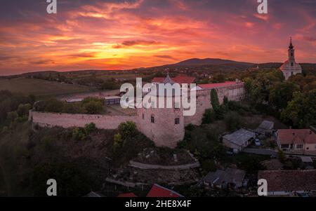 Scatto aereo al tramonto della chiesa fortificata di Pecsvarad e del castello con torre, porta sulla cima di una collina nella contea di Baranya Ungheria Foto Stock