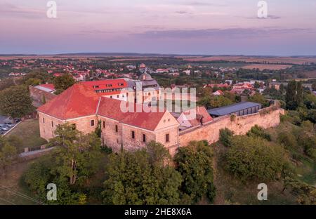 Scatto aereo al tramonto della chiesa fortificata di Pecsvarad e del castello con torre, porta sulla cima di una collina nella contea di Baranya Ungheria Foto Stock