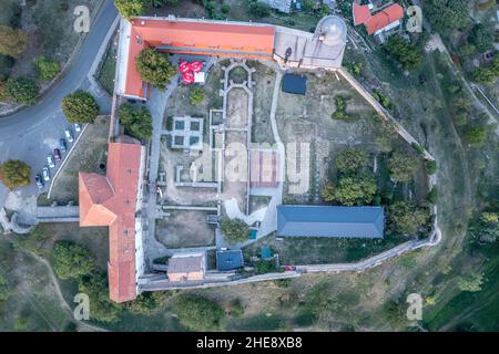 Scatto aereo al tramonto della chiesa fortificata di Pecsvarad e del castello con torre, porta sulla cima di una collina nella contea di Baranya Ungheria Foto Stock