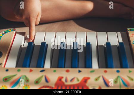 Ritratto in primo piano di un dito indice di un ragazzo che preme sui tasti di un pianoforte giocattolo. Concetto di hobby. Apprendimento divertente. Foto Stock