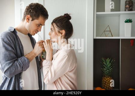 Vista laterale ravvicinata di una coppia che condivide un drink in cucina. Trascorrere la mattina insieme. Foto Stock