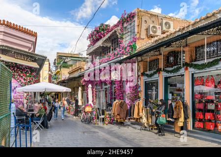 Un negozio decorato in modo colorato e un cafe' sul marciapiede con fiori rosa e magenta vicino al mercato delle pulci di Monastiraki ad Atene, in Grecia. Foto Stock