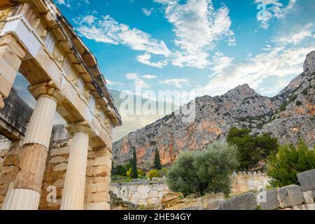 Vista della montagna e delle rovine presso l'antico sito oracolo di Delfi, Grecia, con il Tesoro Ateniano in primo piano. Foto Stock