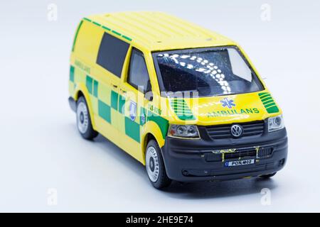 Umea, Norrland Svezia - 13 dicembre 2021: Auto da ambulanza giocattolo indossata in giallo e verde su sfondo bianco Foto Stock