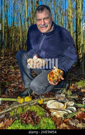 Drebkau, Germania. 06th Jan 2022. Lutz Helbig, consulente di funghi, mostra una piccola selezione di veri funghi invernali in una foresta di Lusatia. Si possono vedere i funghi di ostrica (davanti a destra e a destra), i solchi comuni di velluto (nella mano sinistra), l'orecchio di Giuda (davanti al muschio) e il giallo dorato tremante (M. sui rami). (A dpa 'Judasohr, Samtfußrübling und Co - im Winter lohnt die Pilzsuche') Credit: Patrick Pleul/dpa-Zentralbild/dpa/Alamy Live News Foto Stock