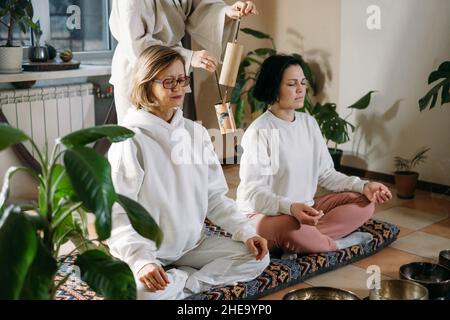 Gruppo o gente guarigione del suono, massaggio di vibrazione e terapia alternativa. Cura della salute mentale, meditazione e relax. Terapista che gioca a diverse età Foto Stock