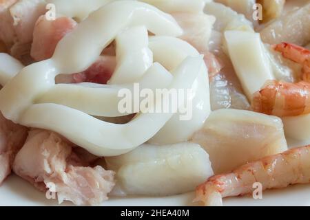 Alcuni gamberi su calamari di rana pescatrice e nasello pronto per cucinare casseruola di pesce. Foto Stock