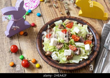 Cibo per le vacanze, insalata di pasqua. Insalata con cavolo cinese, feta, pomodori ciliegini e tonno in scatola e condimento all'aceto su un tavolo festivo. Foto Stock