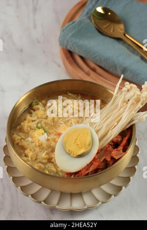 Tradizionale noodle ramyeon coreano con tuorlo d'uovo, peperoncino, kimchi in una tradizionale pentola coreana, piccante Ramyeon coreano Instant noodle un tradizionale Foto Stock