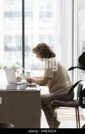 Concentrato vecchia donna anziana calcolo bollette di utilità. Foto Stock