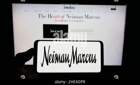 Persona che tiene uno smartphone con il logo del rivenditore di lusso statunitense Neiman Marcus Group Inc. Sullo schermo di fronte al sito Web. Mettere a fuoco sul display del telefono. Foto Stock
