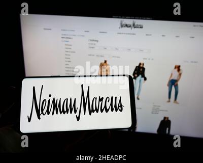 Persona che tiene il telefono cellulare con il logo del rivenditore di lusso americano Neiman Marcus Group Inc. Sullo schermo di fronte alla pagina web. Mettere a fuoco sul display del telefono. Foto Stock