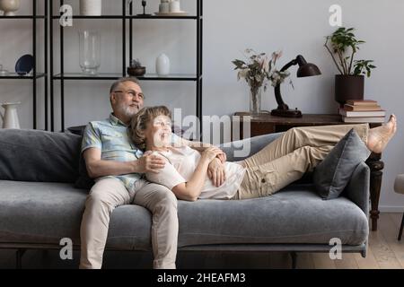 Rilassato felice coppia vecchia rilassarsi su un comodo divano. Foto Stock