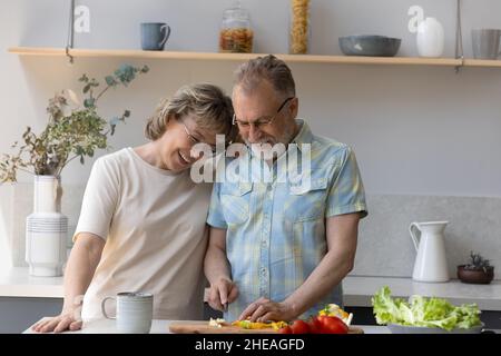 Gioiosa coppia di famiglia di mezza età che cucinano in cucina moderna. Foto Stock