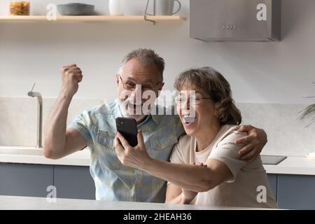 Coppia anziana con grande gioia che celebra il successo di internet mobile. Foto Stock