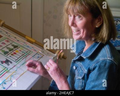 Sorridente donna anziana che fa punto trasversale all'interno, Regno Unito Foto Stock