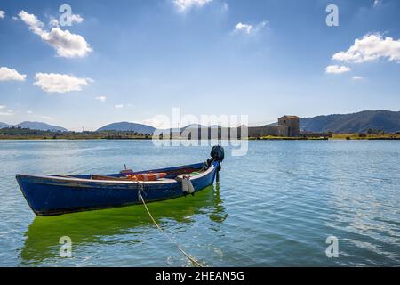 Barca sul mare. Vecchia barca da pesca dipinta di blu legata con la corda al mare Foto Stock