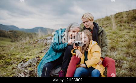 Bambina con madre e nonna scattando foto in cima alla montagna in autunno. Foto Stock