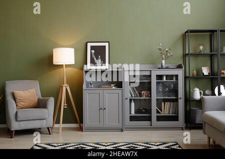 Immagine di un moderno soggiorno con poltrona, lampada e libreria in appartamento Foto Stock