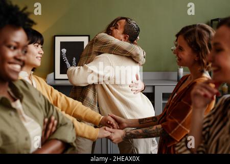 Gruppo di amici felici che si abbracciano e si salutano durante il loro incontro a casa Foto Stock