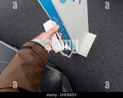 Mano maschio che si prepara a caricare la sua auto elettrica accanto al super caricatore dedicato - POV Foto Stock