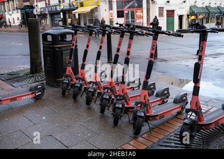Voi eScooter noleggio posto parcheggio il 12th dicembre 2021 a Birmingham, Regno Unito. Un sistema di condivisione scooter è un servizio di trasporto condiviso nel quale gli scooter elettrici, detti anche e-scooters, sono messi a disposizione per il noleggio a breve termine. Gli e-scooters sono solitamente ancorkless, il che significa che non hanno una sede fissa e sono lasciati fuori e prelevati da determinate posizioni nell'area di servizio. Foto Stock