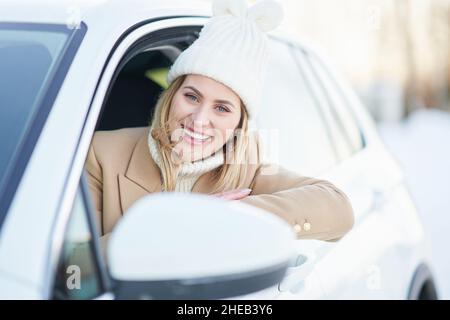 Donna felice guida auto in inverno nevoso Foto Stock