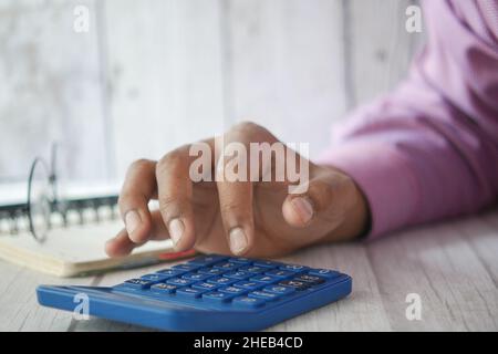 Primo piano della mano dell'uomo utilizzando la calcolatrice Foto Stock