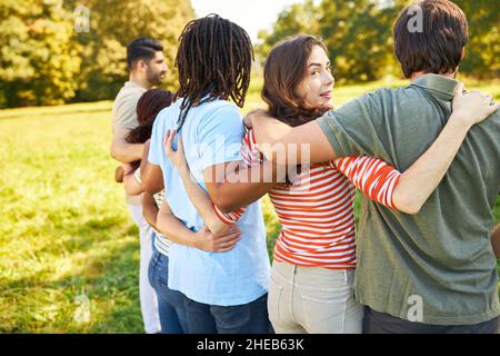 Gruppo di giovani abbracciano come amici o studenti in natura in estate Foto Stock