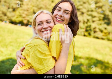 Due giovani donne come migliori amici si abbracciano felicemente nel parco in estate Foto Stock