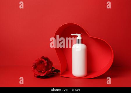 Cosmetici, moisturizer, shampoo bottiglia che rimane nel cuore con fiore rosa su sfondo rosso. san valentino, cura della pelle con amore Foto Stock