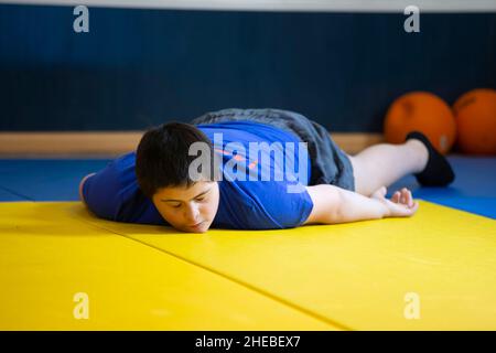 Bielorussia, la città di Gomel, 23 giugno 2021. Judo club. Un bambino con sindrome di Down si trova su un tappetino in palestra. Foto Stock