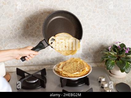 donna che cucinano frittelle in cucina. Colazione vegetariana Foto Stock