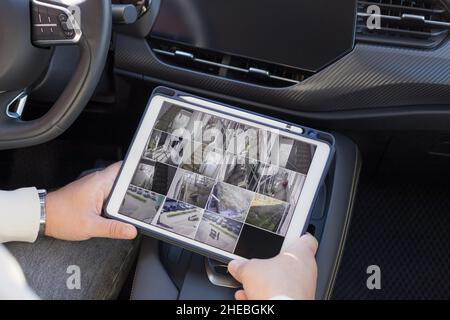 Uomo che controlla le telecamere cctv moderne seduti in auto Foto Stock