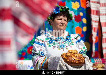 Una donna bielorussa o Ucraina anziana in costume nazionale con una pagnotta. Foto Stock