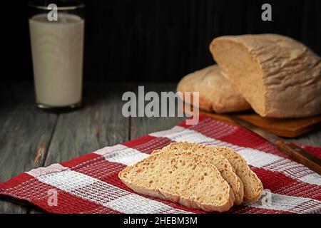 Pane fatto in casa appena sfornato con un bicchiere di latte sul tavolo Foto Stock