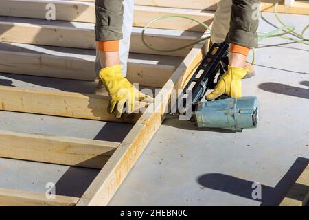 Un carpentiere per chiodare travi di legno con un martello pneumatico Foto Stock