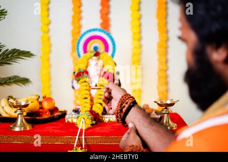 Fuoco sulla mano, spalla colpo di santo, uomo di dio che offre mangalaarthi a lord ganesh idol durante la celebrazione del festival a casa - concetto di tretitional Foto Stock