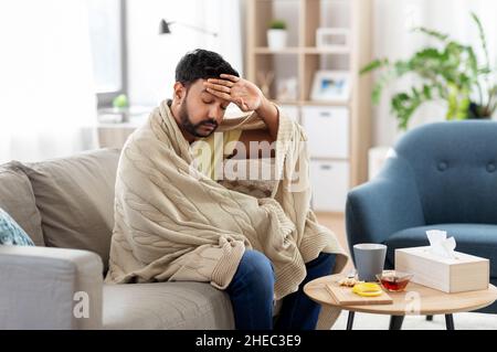 giovane malato in coperta che ha mal di testa o febbre Foto Stock