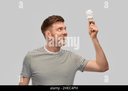 uomo giovane sorridente che tiene la lampadina Foto Stock